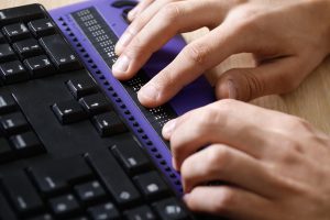User on keyboard with braille pad
